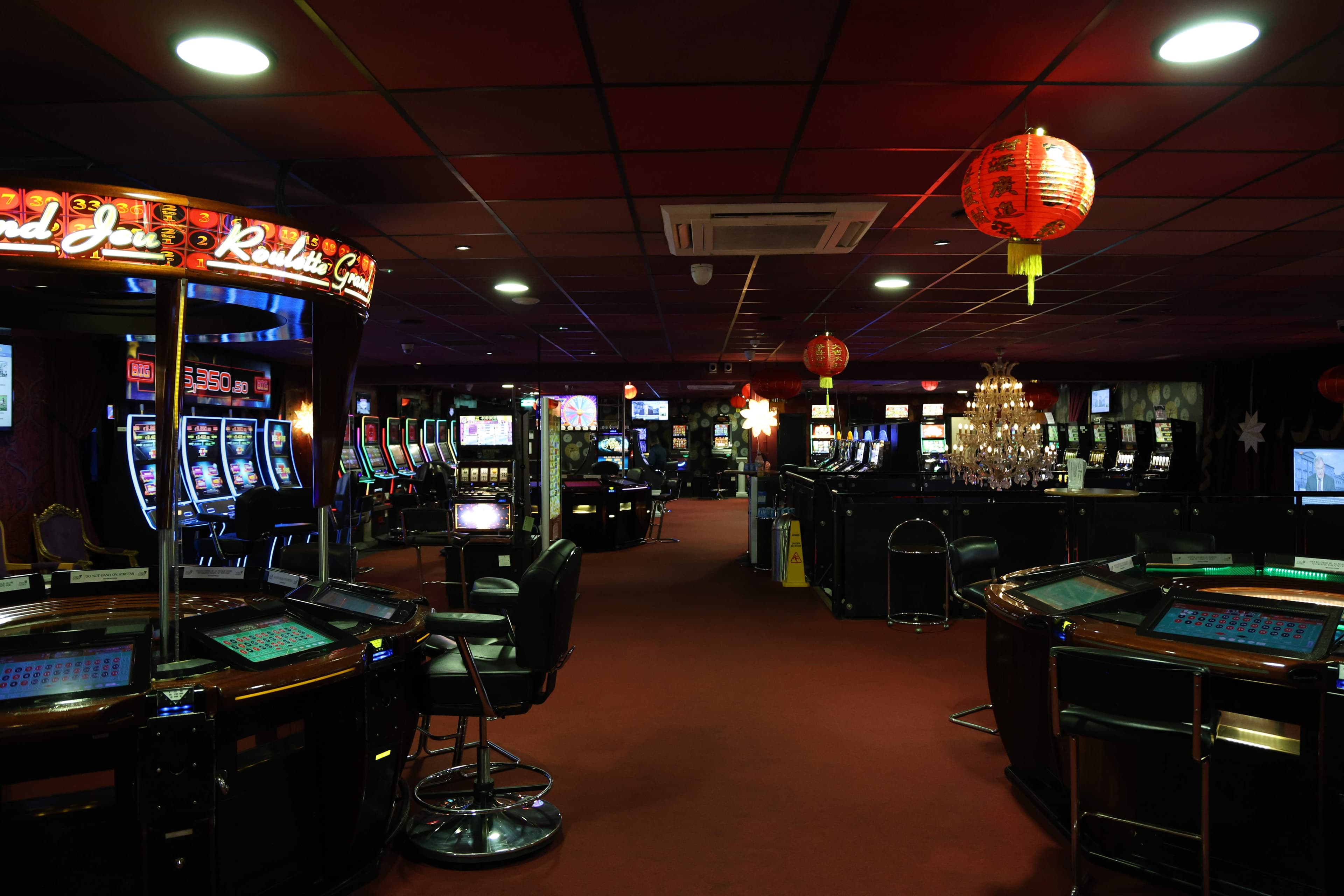 Wide casino floor with roulette tables and chandeliers